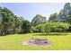 Backyard featuring a fire pit surrounded by lush green grass and mature trees at 1490 Twin Manor Dr, Loganville, GA 30052