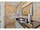 Bathroom featuring stone-tiled walls, frameless glass shower, and a black granite countertop at 571 Morgan Ne St, Atlanta, GA 30308