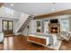 Open-concept living area featuring a stone fireplace, hardwood floors, and a staircase at 7255 Old Rico Rd, Chattahoochee Hills, GA 30268
