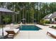 A luxurious pool with lounge chairs, umbrellas, and natural landscaping provides a tranquil outdoor experience at 7255 Old Rico Rd, Chattahoochee Hills, GA 30268
