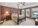 Bedroom with four-poster bed, lake view, tray ceiling, and neutral colored carpet at 2045 Calmwater Ct, Suwanee, GA 30024