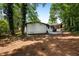 View of the home's rear exterior and expansive backyard surrounded by lush trees at 4720 Shoshonee Trl, College Park, GA 30349