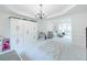 Bright living room with chandelier, built-ins, and neutral carpet flowing into the sunlit sitting area at 9195 Tuckerbrook Ln, Alpharetta, GA 30022