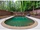 A backyard pool featuring stone accents, wood fence, mature trees, and manicured landscaping at 9195 Tuckerbrook Ln, Alpharetta, GA 30022