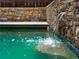 Close-up of a stone waterfall feature in a swimming pool, creating a relaxing ambiance at 9195 Tuckerbrook Ln, Alpharetta, GA 30022