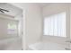 Bright bathroom featuring a soaking tub and a window with sheer white curtains at 131 Prominence Ct, Canton, GA 30114