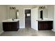 Bathroom with tiled floor, double sink vanity with dark cabinets, and well lit mirrors at 3488 Woodshade Dr, Loganville, GA 30052