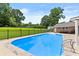 A backyard pool surrounded by a stone patio, a black iron fence and a well-manicured lawn with mature trees at 4010 Hamilton Mill Rd, Buford, GA 30519