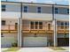 View of multi-story townhome featuring a wooden deck above the garage with neutral paint colors and a well-lit entry at 1240 Ainsworth Aly # 39, Sugar Hill, GA 30518