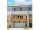 View of multi-story townhome featuring a wooden deck above the garage with neutral paint colors and a well-lit entry at 1240 Ainsworth Aly # 39, Sugar Hill, GA 30518