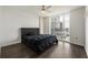 This bedroom features a large window with city views, dark hardwood floors, and a stylish gray tufted headboard at 3475 Oak Valley Rd # 1850, Atlanta, GA 30326