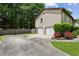 Two-car garage with an expansive driveway, complemented by landscaping and vibrant red roses at 4192 Alaina Cir, Austell, GA 30106
