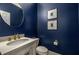Stylish powder room features a round mirror and elegant gold fixtures against a blue painted wall at 626 Kimberly Ne Ln, Atlanta, GA 30306