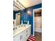 Blue nautical-themed bathroom featuring a double vanity, white cabinets, and a tub with white tile surround at 190 Country Club Dr, Hiram, GA 30141