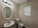 This bathroom has a pedestal sink, oval mirror, and toilet, complemented by a modern light fixture and window with blinds at 1720 New Orleans Way, Mcdonough, GA 30252