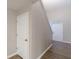 Hallway with wood-look flooring, neutral paint, and multiple doors, with staircase leading to upper level at 1720 New Orleans Way, Mcdonough, GA 30252