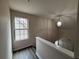 Bright hallway with a window providing natural light, neutral walls, and a view of the staircase with wood-look flooring at 1720 New Orleans Way, Mcdonough, GA 30252