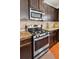 Close-up of a stainless steel stove and microwave oven with beautiful granite countertops and dark wood cabinetry at 2109 Cape Ivey Ct, Dacula, GA 30019