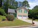 Charming two-story home with a well-manicured lawn, attached garage, and inviting green door at 5517 Rock Shoals Way, Atlanta, GA 30349