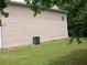 Exterior view of home showcasing beige siding, green lawn, and visible HVAC unit at 5517 Rock Shoals Way, Atlanta, GA 30349