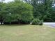 Expansive grassy front yard with mature trees and landscaping, offering a serene and inviting atmosphere at 5517 Rock Shoals Way, Atlanta, GA 30349