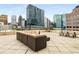 Spacious rooftop deck with city skyline views, featuring a large sectional sofa and picnic table at 1421 Peachtree Ne St # 203, Atlanta, GA 30309