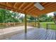 Large, covered deck with wooden floors, railings, and support beams perfect for entertaining outdoors at 1492 Harbins Rd, Norcross, GA 30093
