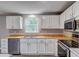 Bright kitchen featuring white cabinets, laminate countertops, and stainless-steel dishwasher at 1492 Harbins Rd, Norcross, GA 30093