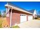 Garage featuring two white garage doors, brick siding, and a well-maintained lawn with side access at 111 Dixson Rd, Bowdon, GA 30108