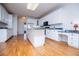The kitchen features white cabinetry, an island, modern appliances and hardwood floors at 111 Dixson Rd, Bowdon, GA 30108