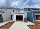 Rear exterior view of a new townhome with a spacious, attached one-car garage and exposed aggregate driveway at 5108 Arista Dr, Douglasville, GA 30135