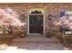 Elegant home entrance with ornate glass doors, brickwork, decorative trees, and traditional lighting at 9995 Huntcliff Trce, Atlanta, GA 30350