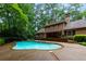 Inviting backyard pool area with brick retaining wall, lush landscaping, and serene wooded surroundings at 9995 Huntcliff Trce, Atlanta, GA 30350