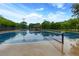 View of a wet tennis court with a covered structure and lighting amidst a scenic backdrop at 9995 Huntcliff Trce, Atlanta, GA 30350