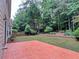 Backyard with brick patio, grassy area, and trees surrounding yard at 4056 Kingsley Park Ct, Peachtree Corners, GA 30096