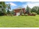 View of a brick home from the large, green backyard and surrounding trees at 516 Main St, Hiram, GA 30141