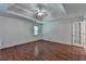 Primary bedroom featuring a tray ceiling, wood floors, a fan and a door to a bathroom at 1464 Yorktown Nw Dr, Lawrenceville, GA 30043