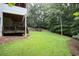 Well-maintained backyard with mature trees, a stone retaining wall, and access to a covered patio at 3510 Woodbury Creek Dr, Cumming, GA 30041