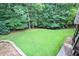 Well-maintained backyard featuring lush green lawn, mature trees, and a patio area at 3510 Woodbury Creek Dr, Cumming, GA 30041