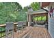Back deck with a bar height table and chairs overlooks a comfortable porch with a stone fireplace at 3510 Woodbury Creek Dr, Cumming, GA 30041