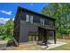 Exterior view of a modern home with dark siding and large windows surrounded by lush trees at 4276 Lindsey Ne Way, Roswell, GA 30075