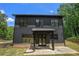 Home's rear exterior showcasing black siding, brick foundation, and covered patio at 4276 Lindsey Ne Way, Roswell, GA 30075