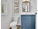 Stylish half bath with blue vanity, framed mirror, white toilet, and decorative wall art above the toilet at 779 Sanders Rd, Cumming, GA 30041