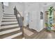 Well-lit foyer with wooden staircase featuring black metal spindles, a potted plant, and decorative wall decor at 779 Sanders Rd, Cumming, GA 30041