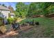 Backyard area with stone fire pit and chairs on gravel, surrounded by trees and grass at 2005 Sweetgum Trl, Cumming, GA 30041