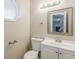 Well-lit bathroom with a white vanity, toilet, octagon window, and decorative mirror at 5786 Longbow Dr, Stone Mountain, GA 30087