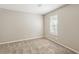 A carpeted bedroom with neutral walls featuring a window with blinds and a minimalist aesthetic at 5786 Longbow Dr, Stone Mountain, GA 30087