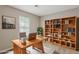 Well-lit office with large wooden desk, bookshelf, rug, and window with horizontal blinds at 5786 Longbow Dr, Stone Mountain, GA 30087