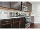 Kitchen featuring stainless steel appliances, white countertops, tiled backsplash and dark wood cabinets at 5830 Keystone Pt, Lithonia, GA 30058