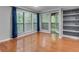 An ample living room with hardwood floors, a fireplace with shelving, and windows with a wooded view at 1015 Dunbar Dr, Dunwoody, GA 30338